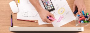 Hand highlighting papers on a desk.