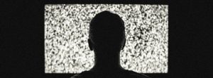 Back of man's head staring at fuzzy tv screen.