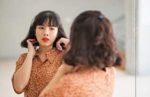 Woman looking in mirror fixing her hair.