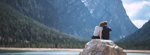 Couple sitting on a rock overlooking mountains.