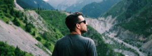 Man hiking in the mountains wearing sun glasses.