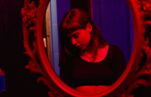 a woman in black shirt looking down reflection through a mirror.