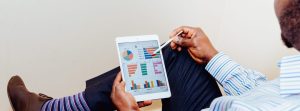 Man sitting and looking at graphs on an ipad.