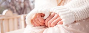 Close up image of woman's hands clutching her oversized sweater sleeves.