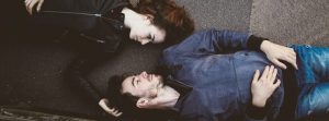 Man & woman laying together looking at each other.