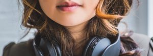 Close up of woman's lower face & neck, her mouth & headphone round her neck in focus.