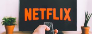 Hand holding a remote with Netflix on the tv.