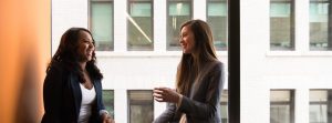 Two women smiling & having a conversation.