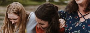 3 girl friends hugging each other and laughing.