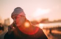Man on phone outside with orange lens flare.