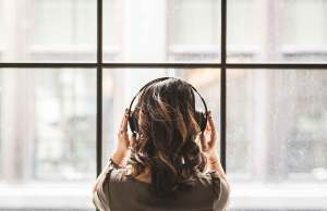 Woman wearing big headphones looking out a window.