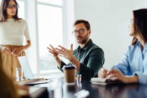 Man talking to female coworkers in a conference room