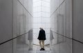 Older man walking between white walls.