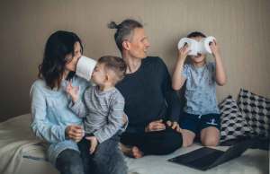 Family sitting with two young boys playing with rolls of toilet paper.