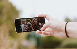 Teenagers taking selfie in iphone screen.