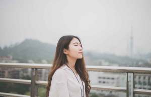 woman in white shirt standing on bridge by mountain.