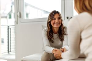 Woman smiling holding therapists hands for support.