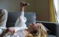 Woman laying on couch holding her phone over above her.