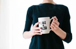 person holding white coffee cup thats says "like a boss" in black sweater.