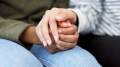 Black woman holding her hands in her lap while a white woman holds her hands.