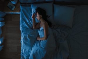 Woman happily sleeping in bed on her side tucked in.