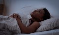 Woman lying awake in bed at night looking up thoughtfully