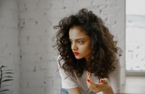 Thoughtful woman with red lipstick and red fingernails.