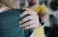 Out of focus man grabs woman's shoulder.