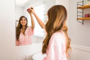 Woman drawing a heart on mirror with lipstick and smiling.