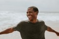 Cheerful man enjoying life on the beach with his arms out.