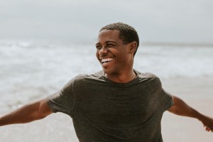 Cheerful man enjoying life on the beach with his arms out.