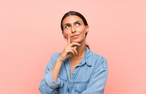 Woman over isolated pink background thinking an idea.