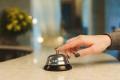 Hand ringing a bell on a counter.