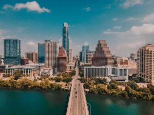 Austin, Texas skyline with skyscrapers on the water and a small bridge over the water.