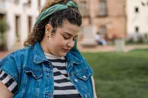 Woman in denim vest and headband looking at the ground outside
