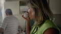 Woman drinking coffee at home with partner in background