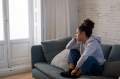 Woman in gray sweatshirt on a gray couch