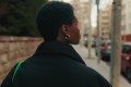 Woman walking alone on a city street, seen from behind, looking ahead