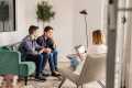Two men sitting on a green couch speaking to a couples therapist