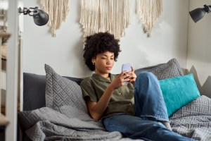 Young woman scrolling on her phone in bed