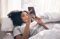 Women laying in bed staring at her phone, using an AI chatbot for mental health