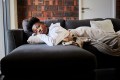 Young woman laying on couch looking bored in her living room, possibly feeling anhedonia
