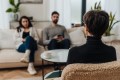Back view of female family psychologist in glasses having conversation with couple during couples therapy session
